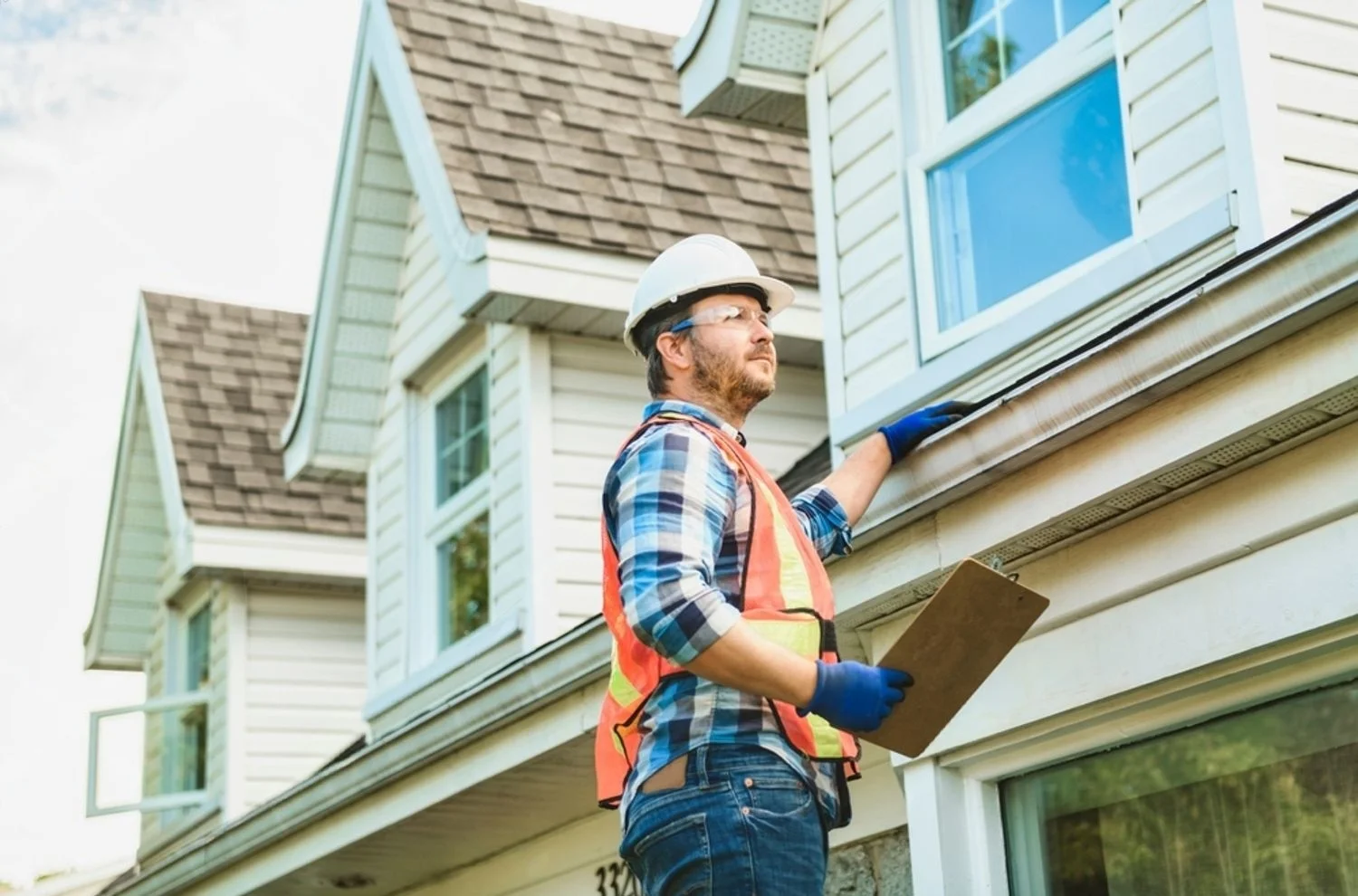 Professional construction worker inspecting house exterior for rendering services Essex Hertfordshire North London - RapidRend